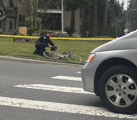 Police officer examining a crashed bicycle next to a road